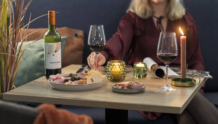 Woman at the table with a game platter and red wine.