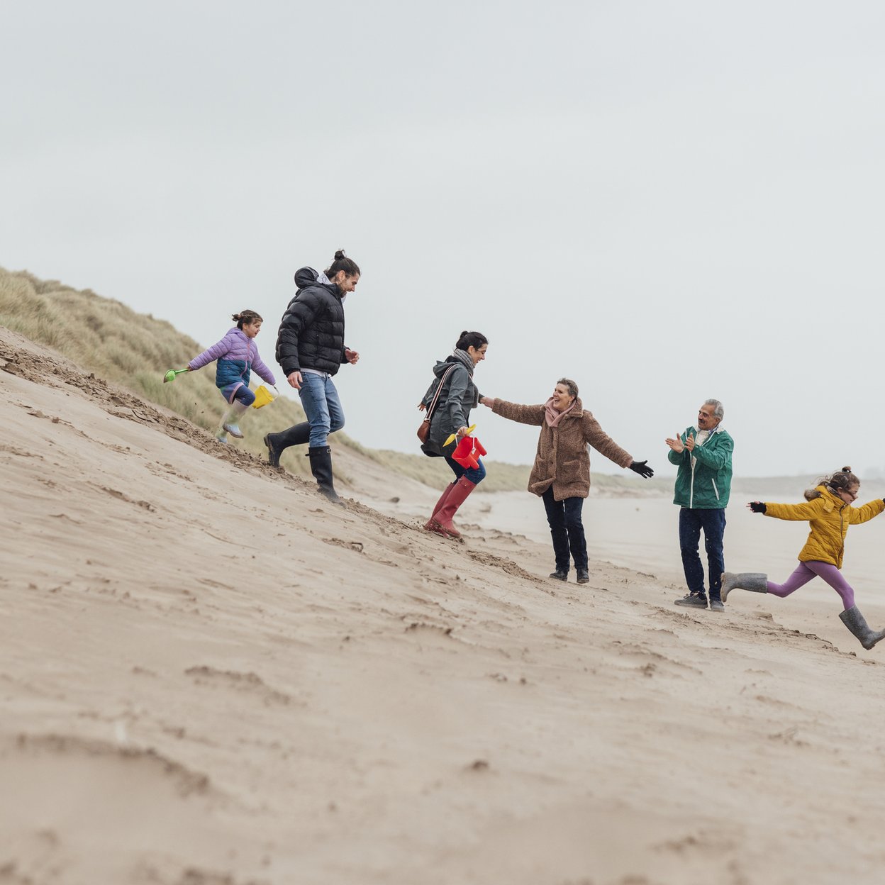 Een familie dat samen aan het uitwaaien is op het strand.