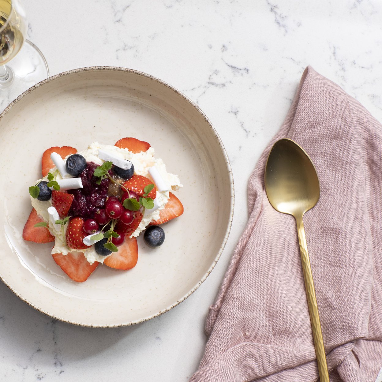 Een dessert met rood fruit geserveerd met een glas wijn